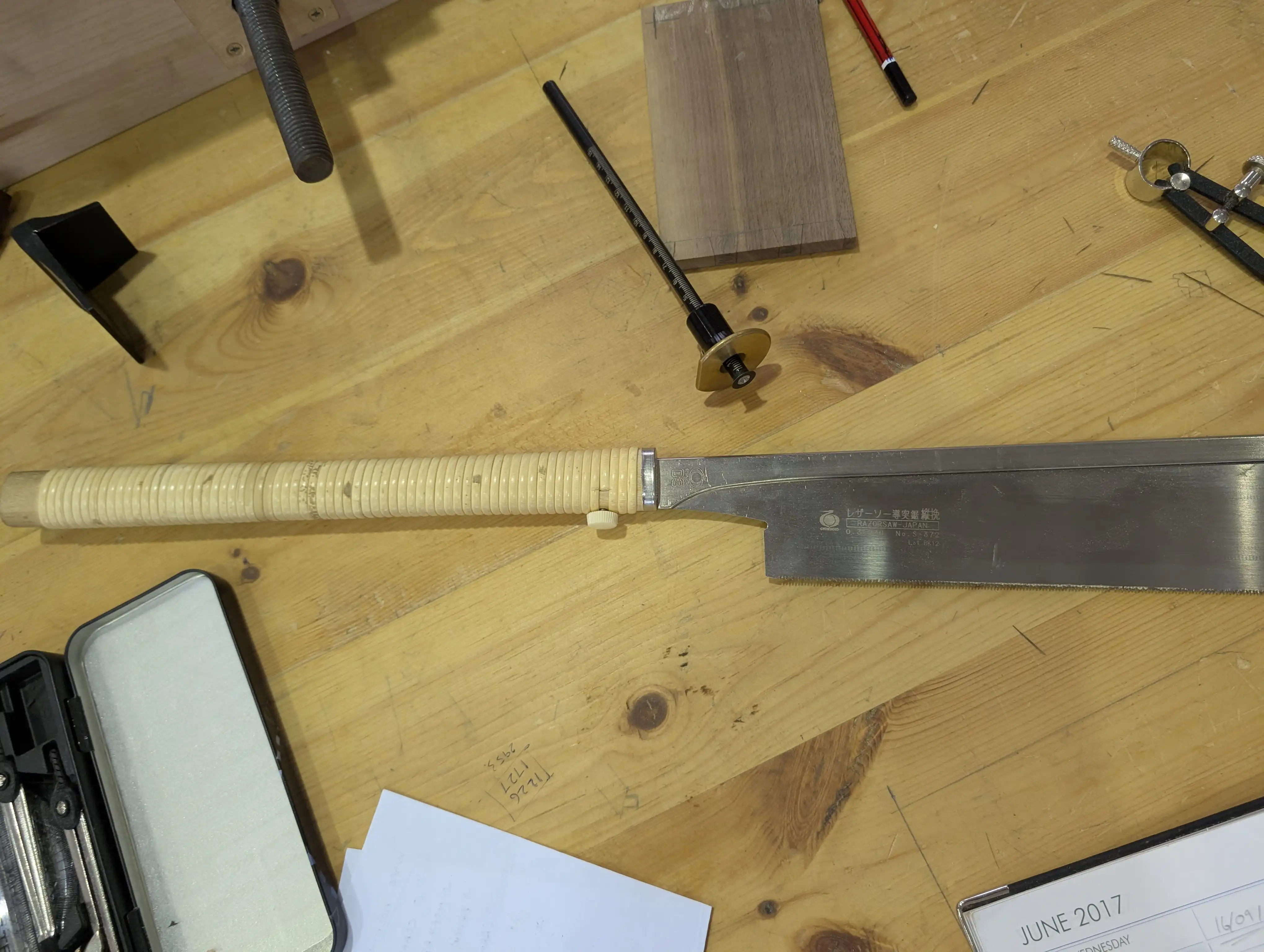 A Japanese Dozuki saw lying on a workbench.